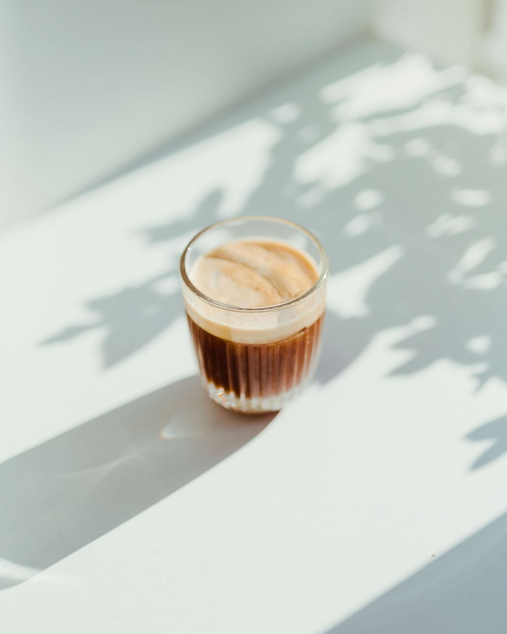 a glass cup with warm coffee made using unprocessed Adri Wellness' stevia leaf powder as the sweetener placed on a white surface