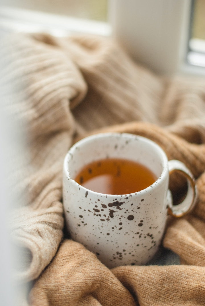 a warm white coloured cup of Adri Wellness' Organic Tulsi and Ashwagandha Tea