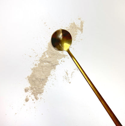 Adri Wellness's fine organic Ashwagandha powder scattered on a white surface with a golden spoon