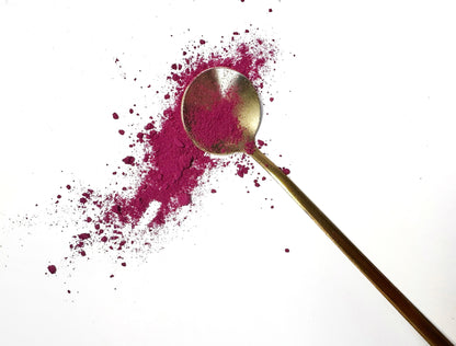 Adri Wellness's fine organic Beetroot powder scattered on a white surface with a golden spoon
