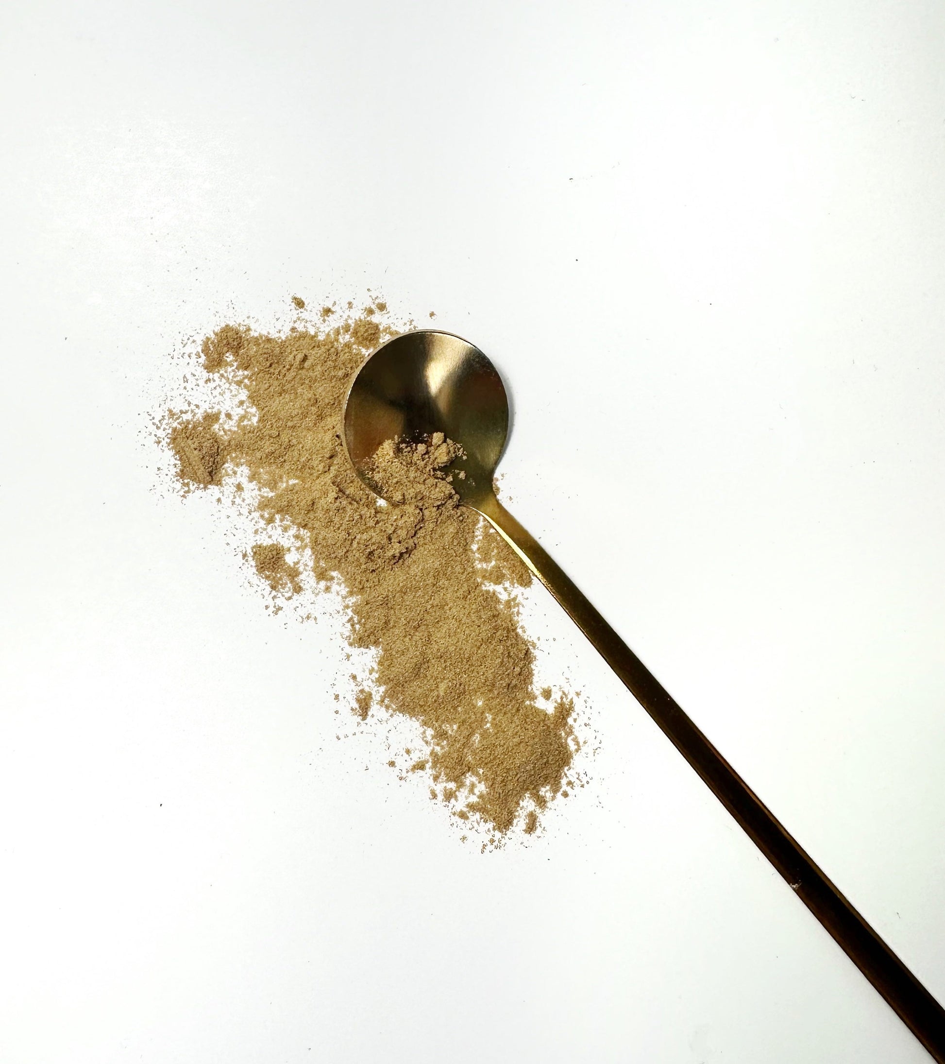 Adri Wellness's fine organic Chamomile powder scattered on a white surface with a golden spoon