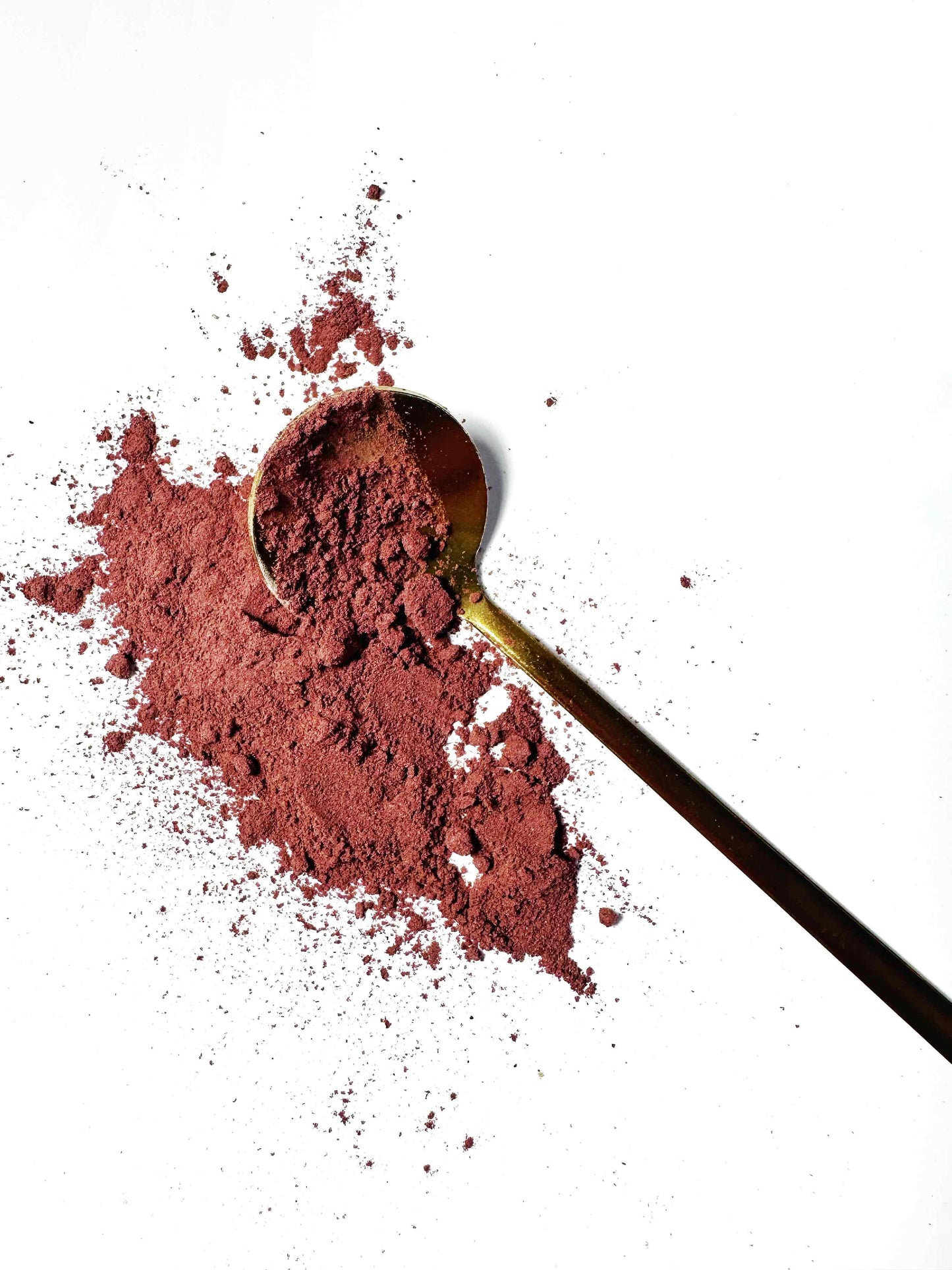 Adri Wellness's fine organic Hibiscus powder scattered on a white surface with a golden spoon