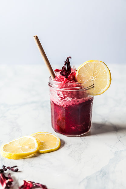 a slush made of Adri Wellness' Beetroot powder in a transparent mason jar garnished with a slice of lemon with a straw 